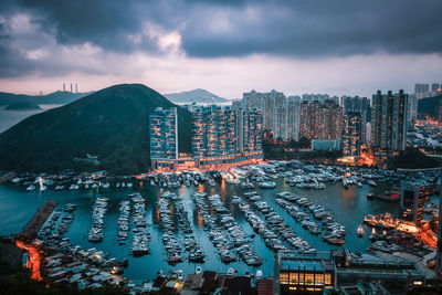 High angle view of illuminated city by sea against sky