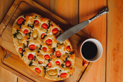 Homemade italian focaccia slices, with tomato and olive oil and a cup of coffee.