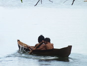 Rear view of people sitting on boat in sea