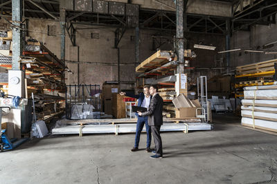 Two businessmen with folder talking in an old storehouse