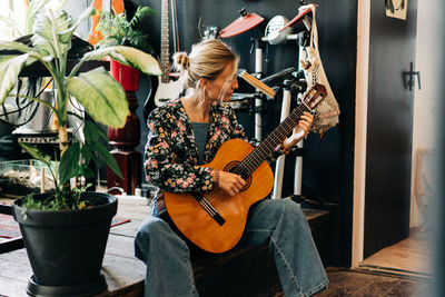 A versatile modern young european woman enthusiastically plays the guitar at a music rehearsal.