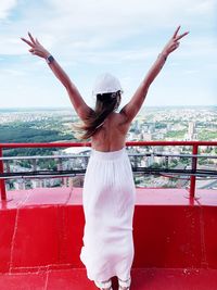 Full length of woman standing by railing against sky