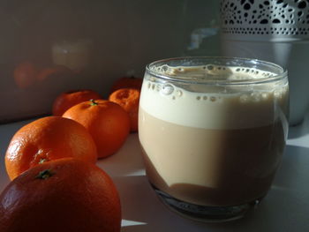 Close-up of coffee in glass with oranges on table