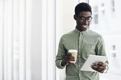 Young man using mobile phone while standing at home