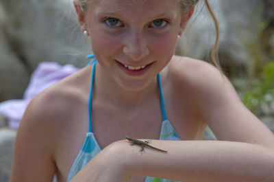 Close-up portrait of smiling girl with lizard on hand