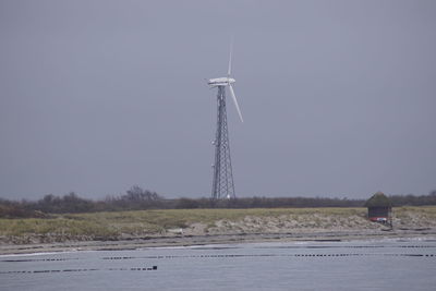 Wind turbine in water against clear sky