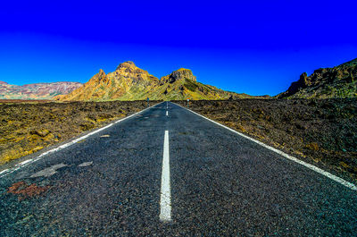 Road amidst mountain against clear blue sky