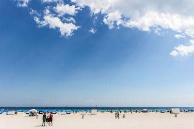 People on beach against blue sky