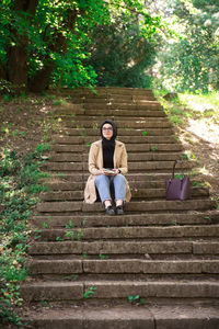 Full length of woman sitting on staircase