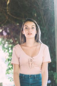 Portrait of beautiful young woman standing against tree