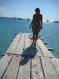 Full length of woman standing by sea on pier