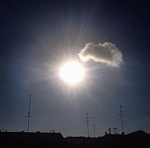 Low angle view of sun shining through clouds