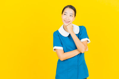 Portrait of a smiling young woman against yellow background