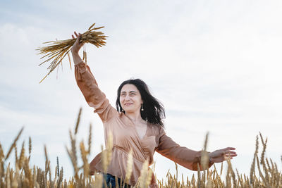 Portrait of smiling young woman with arms raised