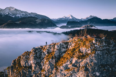 High angle view of man standing on mountain ridge rising above the clouds, hallein, austria