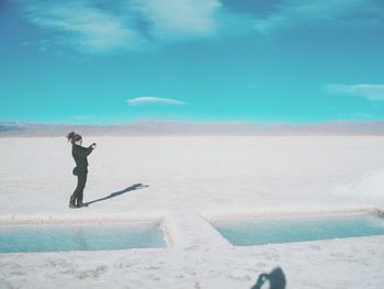 Woman standing on salt pan against sky