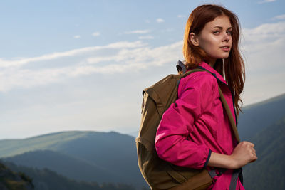 Portrait of young woman standing on mountain against sky