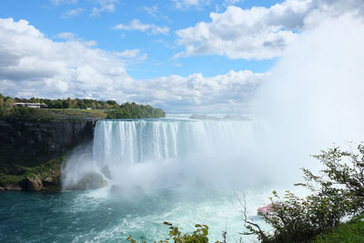 The mist from a waterfall fills the air through a blue sunny sky at niagara falls in canada.