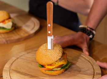 Midsection of man holding burger on table