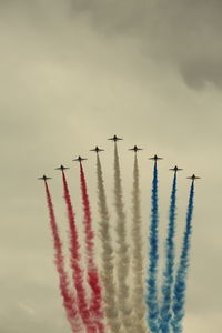 Low angle view of air show against cloudy sky