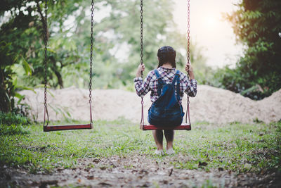 Rear view of girl sitting on swing