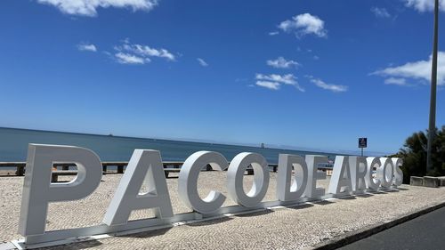 Text on sand at beach against blue sky