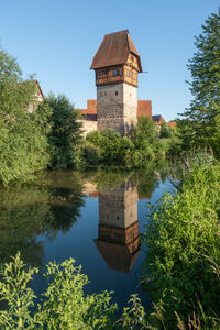 Medieval citywall with tower  by moat as reflection  against sky
