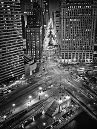 High angle view of illuminated street amidst buildings in city at night