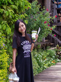 Portrait of young woman standing against plants