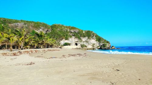 Scenic view of beach against clear blue sky