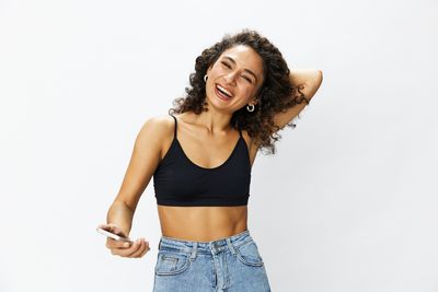 Portrait of young woman standing against white background