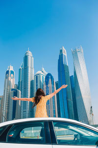 Rear view of woman on modern buildings in city against sky
