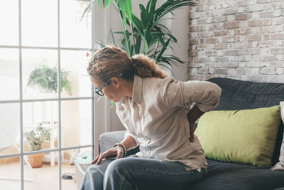 Side view of woman sitting on sofa at home