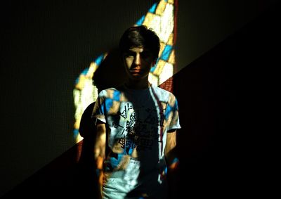 Portrait of young woman standing against black background