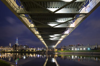 Illuminated bridge over river against sky in city at night