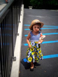 Portrait of cute baby girl with toy standing on road