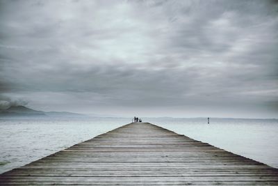 Pier on sea against cloudy sky