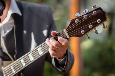 Midsection of well-dressed man playing guitar