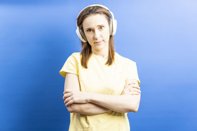 Portrait of young woman standing against blue background