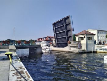 Scenic view of river by buildings against clear sky