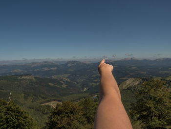 Midsection of person on mountain against sky