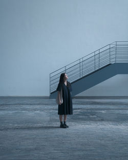 Rear view of woman standing on sea against clear sky