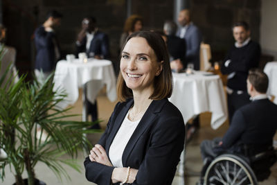 Portrait of happy businesswoman with arms crossed at seminar