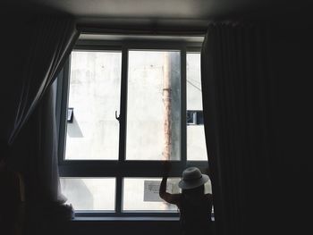 Rear view of man looking through window