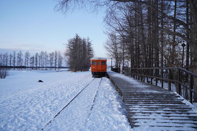 Train on snow covered railroad tracks against sky