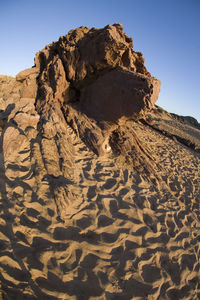 Rock formations on sand against sky