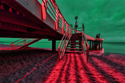 Low angle view of red bridge over sea against sky