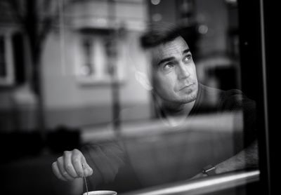 Close-up of man looking through window