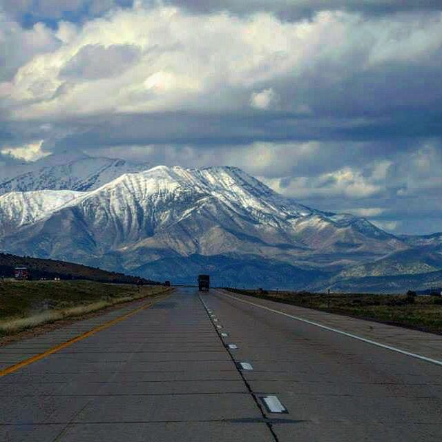 ROAD LEADING TOWARDS SNOWCAPPED MOUNTAINS AGAINST SKY