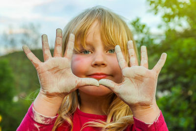 Portrait of cute girl showing her dirty hands in park